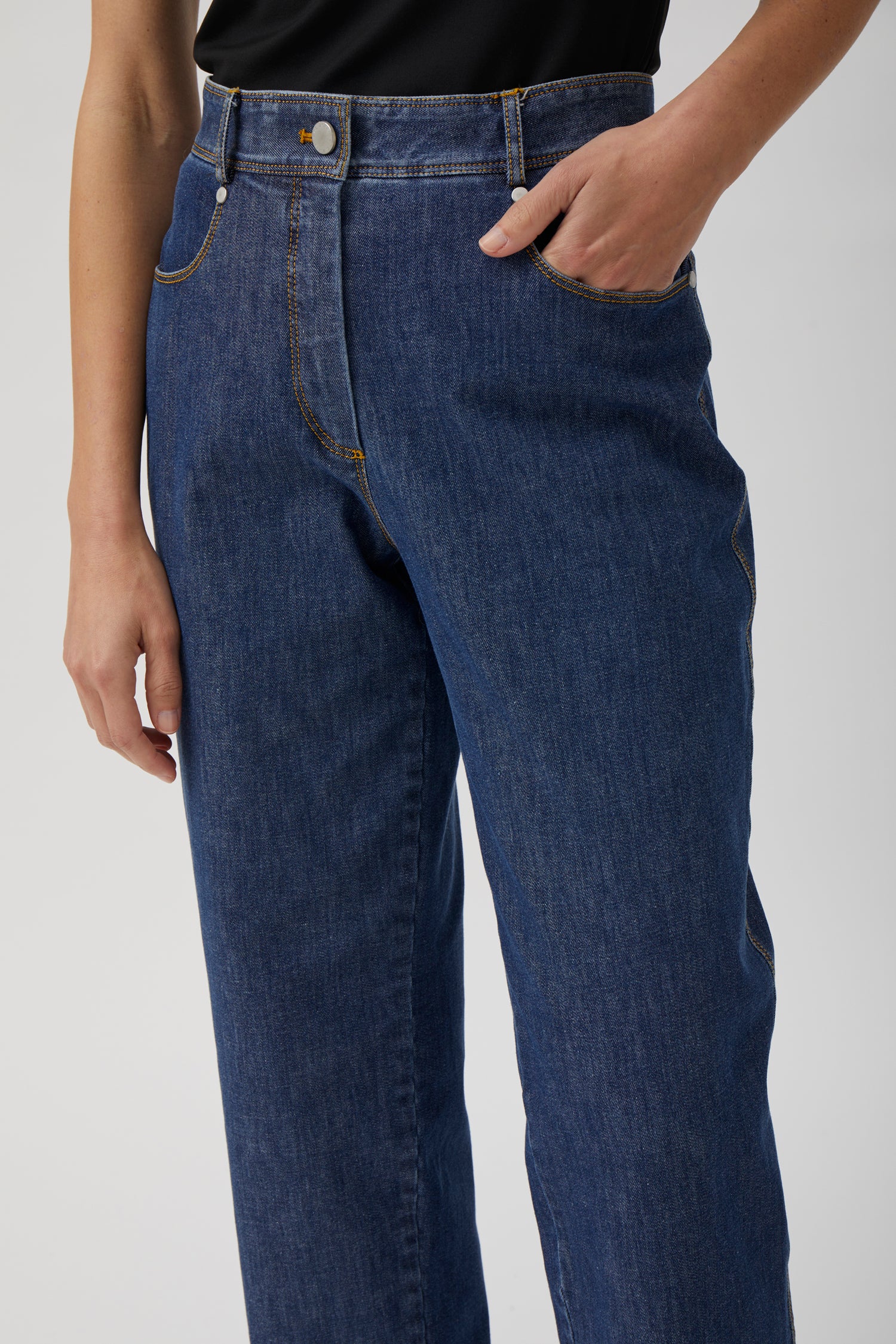 Female model wearing washed blue straight-leg jeans with black fitted top